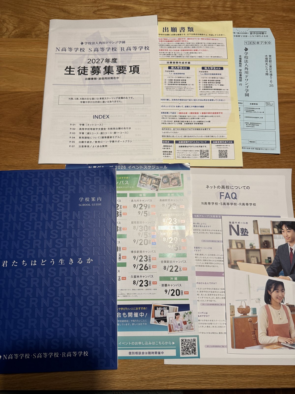 N高等学校の資料請求で届いた7点。2027年度生徒募集要項、黄色い出願書類、返信用封筒、学校案内パンフレット、ネットの高校についてのFAQ、イベントスケジュール、N塾のチラシ